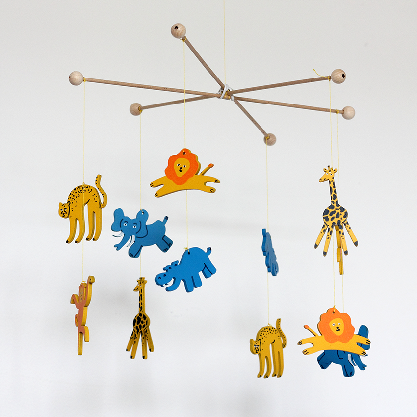 flat wooden cartoon animals painted by hand, hanging on thread as a crib mobile in front of light background