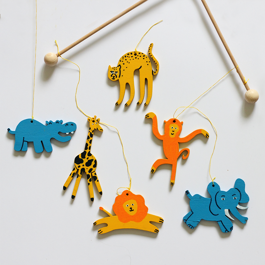 flat wooden cartoon animals painted by hand, used as a crib mobile, laying on a light background